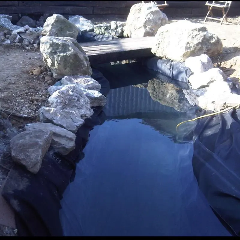 A koi pond built to look like a river running across the garden, with a bridge